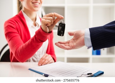 Female car agent giving key to male customer for test drive. Partnership and contract signing.   