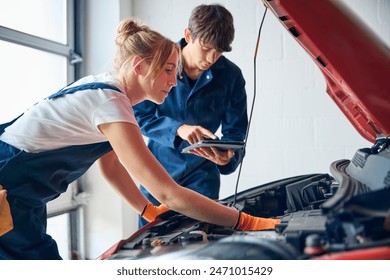 Female Car Auto Mechanic With Trainee Looking Under Bonnet Of Car Using Digital Tablet - Powered by Shutterstock