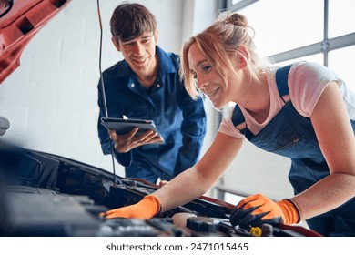 Female Car Auto Mechanic With Trainee Looking Under Bonnet Of Car Using Digital Tablet - Powered by Shutterstock