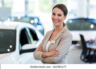 Female Car Dealer Standing In Showroom
