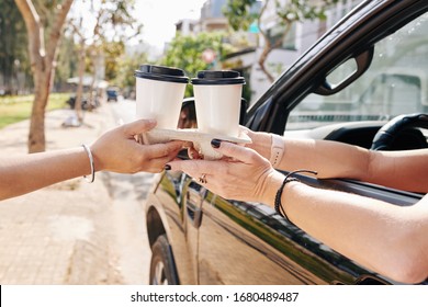 Female Car Driver Buying Two Cups Of Take Out Coffee In Drive Through Cafe