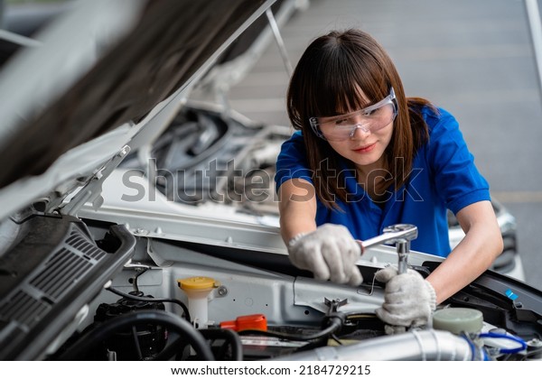 Female car mechanic checking the\
engine of a car A mechanic inspects and maintains the engine of a\
car or vehicle. female mechanic checking engine .Mechanic\
concept
