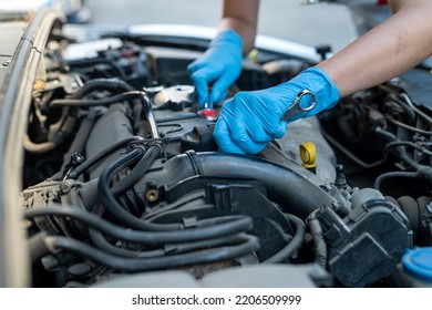 Female Car Service Technician Inspects And Repairs A Customer's Car At A Car Service Center. Checks The Car Under The Body And Suspension System. Vehicle Repair Workshop.