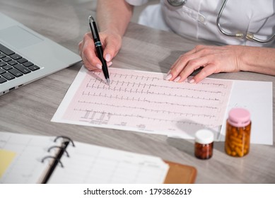 Female Cardiologist Examining An Ecg Graph In Medical Office