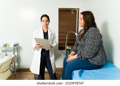 Female Cardiologist Specialist Checking The Lab Results Of An Overweight Young Woman. Female Patient At A Medical Check-up At The Doctor