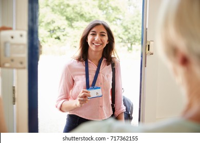 Female care worker on home visit showing her ID, close up