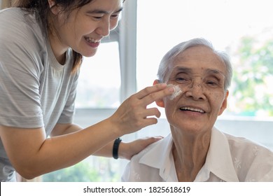 Female Caregiver Assisting To Apply Sunscreen Lotion On The Face Of Senior Woman,granddaughter Using Skin Care Cream For Elderly Sensitive Skin,happy Smiling Grandmother With Sun Block On Facial Skin