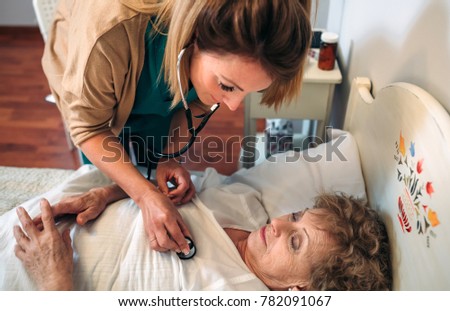 Caregiver auscultating senior woman