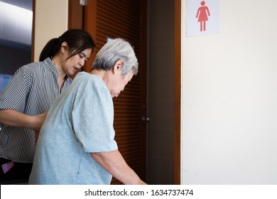 Female Caregiver Is Helping Support Elderly Woman Walk Into The Restroom Carefully,asian Senior With Bladder Control Problem Need To Use The Toilet,old People Suffer From Stress Urinary Incontinence