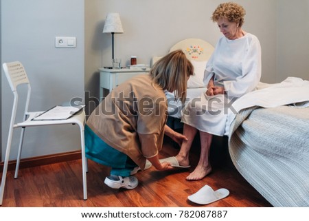 Carer wearing slippers to elderly female patient