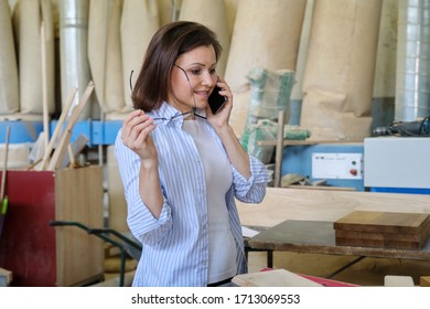 Female Carpenter Designer Working In Carpentry Workshop, Choosing Materials, Talking On Phone. Industrial Business, Woodwork