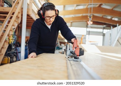 Female Carpenter Or Joiner At Work In A Woodworking Factory In A Low Angle View With Copyspace Of Her Using Power Tools On A Large Wood Panel