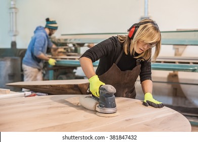Female carpenter Using Electric Sander for wood