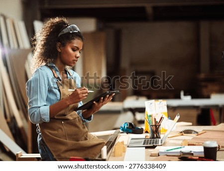 Female Carpenter Using Mobile Device In Workshop For Business Communication Ideal For Showcasing Customer interaction, DIY furniture order handling, and artisan small business workflow visuals