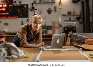 Female carpenter working at laptop in furniture repair workshop. Copy space - Powered by Shutterstock