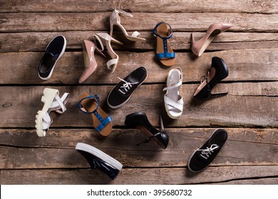 Female casual and luxury shoes. Woman's shoes on aged floor. Footwear laying on old table. So many different shoes.