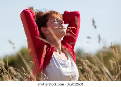 Female Casual Relaxation - Meditating Mature Woman Enjoying Fresh Air In Her Hair With Flower In Her Mouth In Long Dry Summer Field Seeking For Peace,summer Daylight