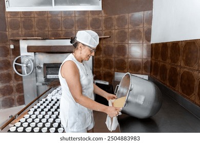 Female caucasian adult baker preparing dough in a commercial kitchen to make muffins - Powered by Shutterstock