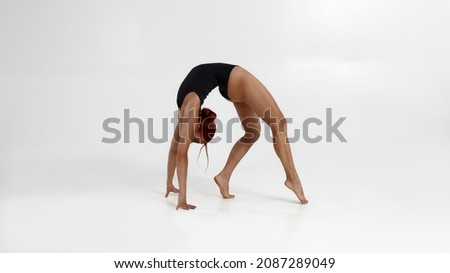 Female caucasian ballet dancer dancing classical ballet dance. Choreography concept. Young flexible woman with red hair barefoot and wearing leotard. Isolated on white background in studio. Copy space