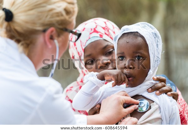聴診器を持つ小さなアフリカの女の子の心臓の鼓動と呼吸を聞く白人の女の子の医師 母親が子どもを持つ の写真素材 今すぐ編集