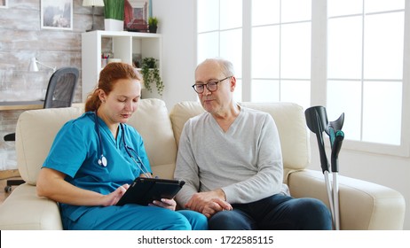 Female caucasian nurse taking notes about elderly man health in bright and cozy nursing home. Caregiver and social worker
