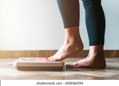 Female checking kilogrammes getting on the scale - self care and body positivity concept - warm flare on left - Shutterstock ID 1858360294