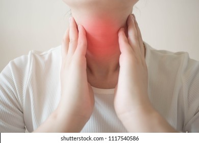 Female checking thyroid gland by herself. Close up of woman in white t- shirt touching neck with red spot. Thyroid disorder includes goiter, hyperthyroid, hypothyroid, tumor or cancer. Health care. - Powered by Shutterstock