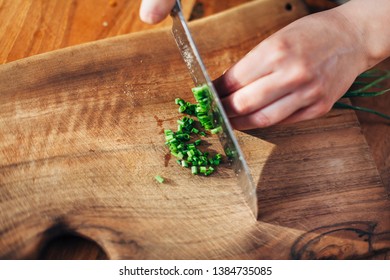 Female Chef Chopping Spring Onions On A Wooden Board