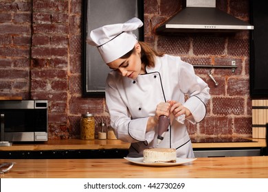 Female chef cook preparing a sweet cake in the kitchen, pouring the chocolate cream on it - Powered by Shutterstock