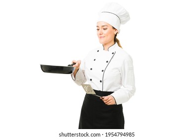 Female chef cooking a delicious dinner at a restaurant. Attractive latin cook frying a new dish with a pan and a spatula against a white background