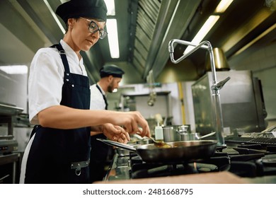 Female chef cooking in the kitchen at restaurant. Copy space. - Powered by Shutterstock