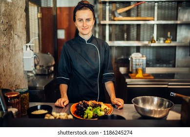 Female chef cooking meat salad on wooden table