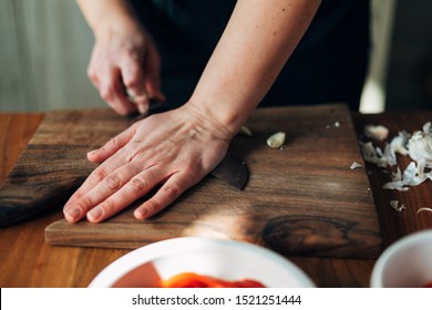 Female Chef Crushing Garlic On A Wooden Board