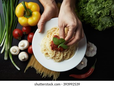 Female chef decorating Italian pasta sauce and basil. Concept of traditional cuisine and healthy meal. 