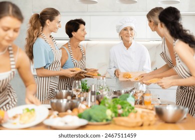 Female chef explains to women visitors of cookery courses for amateurs about delicious and simple way of cooking dietetic and low-calorie poultry meat, chicken - Powered by Shutterstock