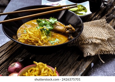 A female chef garnishing her Khao Soi Kai with a lime slide, Khao Soi Kai or Thai noodles curry with egg noodles and chicken drumstick. - Powered by Shutterstock