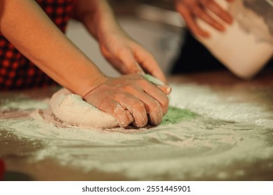 Female chef kneading dough on a floured wooden table in a restaurant kitchen, preparing fresh pasta or pizza with flour - Powered by Shutterstock