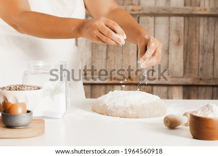 Female chef making shower of flour and ingredients for the dough on the kitchen table. Copy space