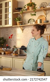 Female Chef Prepares Italian Pasta With Tomatoes And Permesan In A Bright Kitchen In A Rustic Style. Mint Coat Apron. Chef At Home