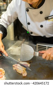 Female Chef Slices Delicious Chicken Teriyaki To Serve The Customer In A Teppanyaki Kitchen.