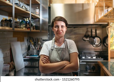 Female chef standing in her kitchen in a small italian style restaurant. Portrait of a young business woman in her bistro