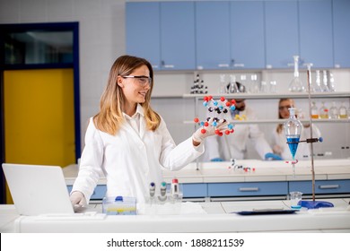 Female chemist with safety goggles hold molecular model in the lab - Powered by Shutterstock