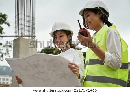 The female chief engineer and her assistant are discussing, planning and inspecting the construction work at the site.