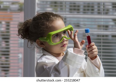 Female Child In Lab Coat With Test Tube And Safety Goggles.