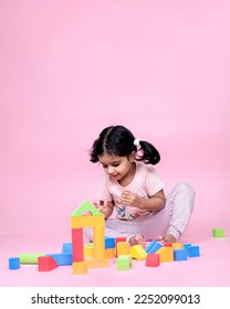 female child playing with colorful toy pink isolated background - Shutterstock ID 2252099013