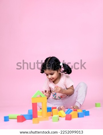 female child playing with colorful toy pink isolated background
