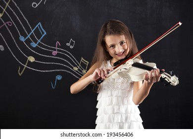 Female child playing the violin next to a blackboard
