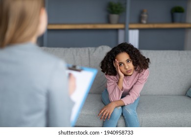Female child psychologist working with upset black girl, teenager patient talking about her feelings