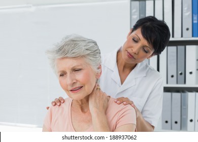 Female chiropractor looking at senior woman with neck pain in the medical office - Powered by Shutterstock