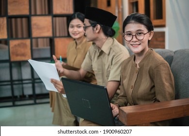 female civil servant smile using laptops and male civil servants holding documents while sitting while working online at home